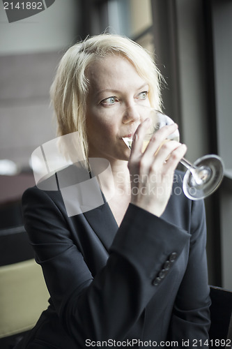 Image of Blonde Woman with Beautiful Blue Eyes Drinking Glass of White Wi
