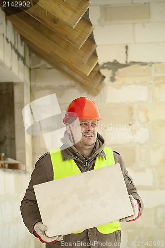 Image of Builder with concrete block near new building