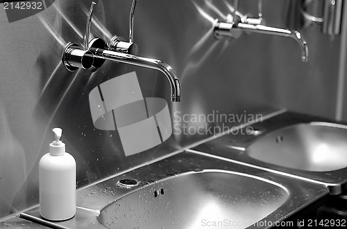 Image of faucets, sinks and liquid soap in a toilet