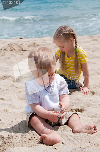 Image of Little girl with brother sitting on the beach