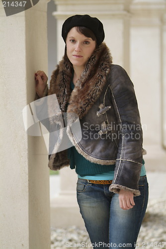 Image of young woman leans at a pillar