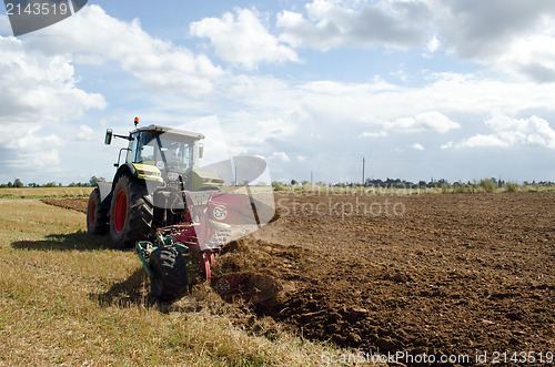 Image of heavy agricultural machine tractor works in field 