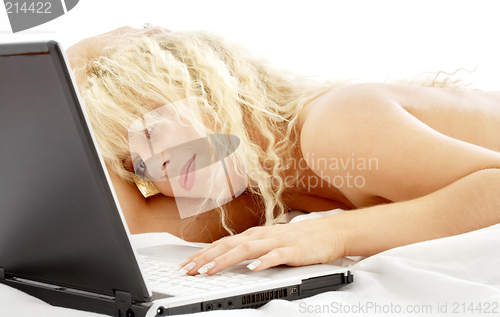 Image of portrait of blond laying in bed with laptop
