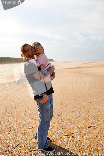 Image of Father holding daughter in arms at the beach