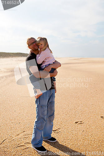 Image of Father holding daughter in arms at the beach