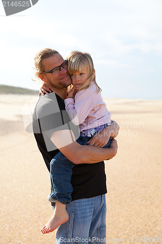 Image of Father holding daughter in arms at the beach