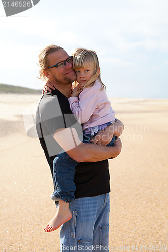 Image of Father holding daughter in arms at the beach