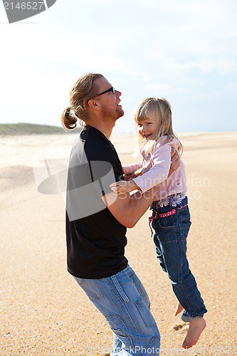 Image of Father holding daughter in arms at the beach