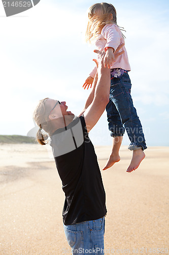 Image of Father throwing daughter in the air at the beach