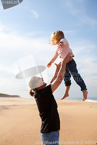 Image of Father throwing daughter in the air at the beach