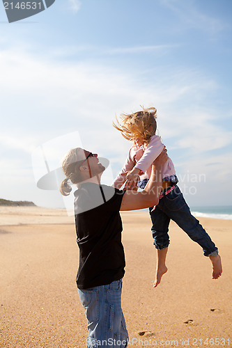 Image of Father throwing daughter in the air at the beach