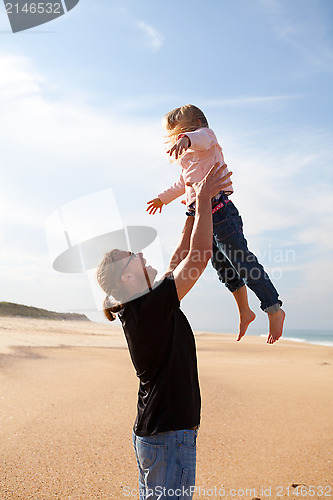 Image of Father throwing daughter in the air at the beach