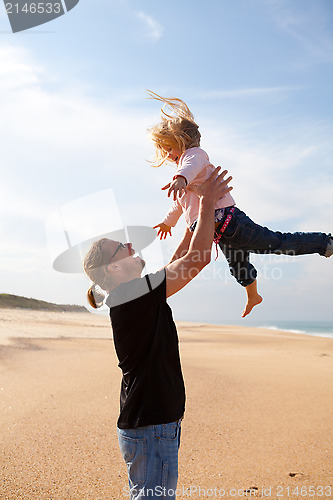 Image of Father throwing daughter in the air at the beach