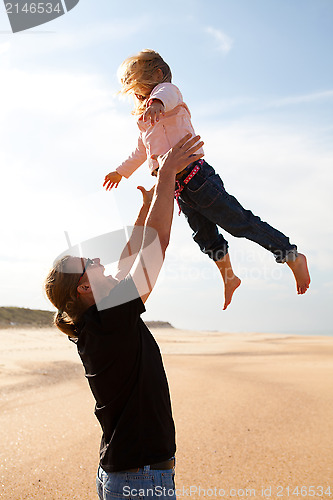 Image of Father throwing daughter in the air at the beach