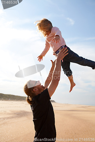 Image of Father throwing daughter in the air at the beach