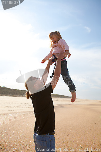 Image of Father throwing daughter in the air at the beach