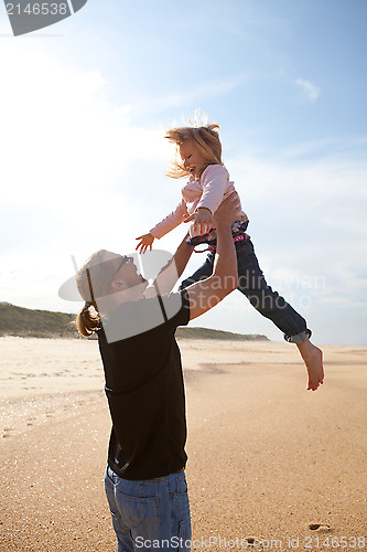 Image of Father throwing daughter in the air at the beach