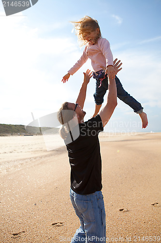 Image of Father throwing daughter in the air at the beach