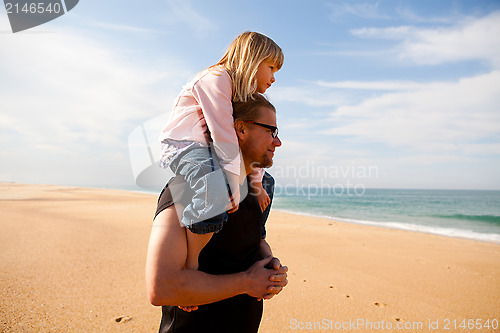 Image of Father carrying daughter on shoulders at the beach