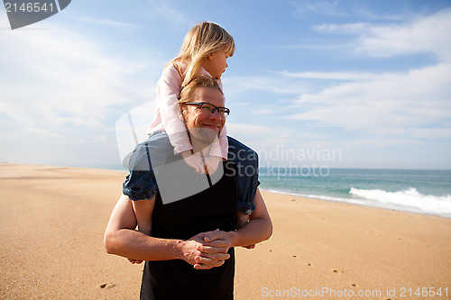 Image of Father carrying daughter on shoulders at the beach