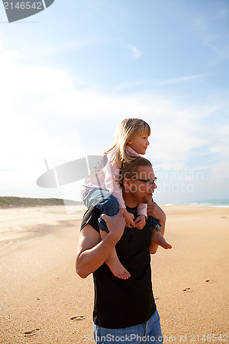 Image of Father carrying daughter on shoulders at the beach