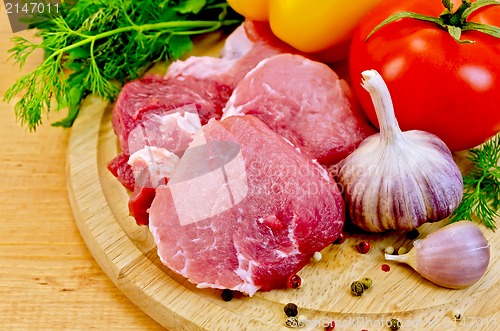 Image of Meat slices on a wooden board with vegetables