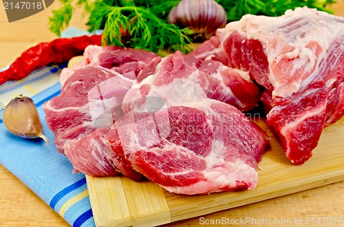 Image of Meat on a wooden board with vegetables