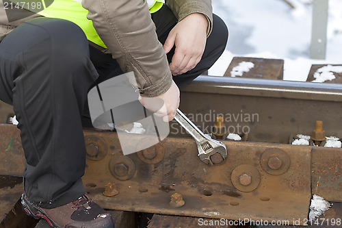 Image of Railroad worker with wrench on the railway bridge fix the nut