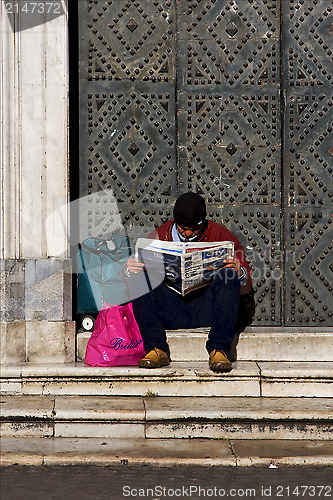 Image of naples and a hompless reading a newspaper