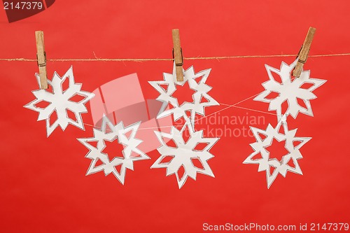 Image of snowflakes produced by child hanging on red background