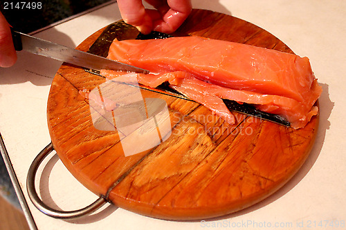 Image of  hand cuts slices of red fish