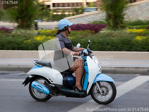 Image of Thai woman rides a scooter. Editorial only.