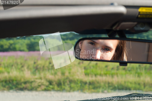 Image of Brunette woman watching on rear-view mirror