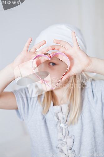 Image of Young girl looking through gingerbread biscuit cutter