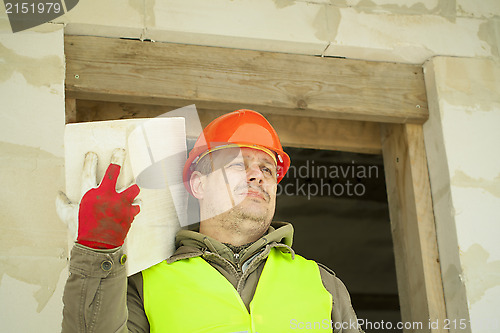 Image of Builder with a concrete block on shoulder at new building