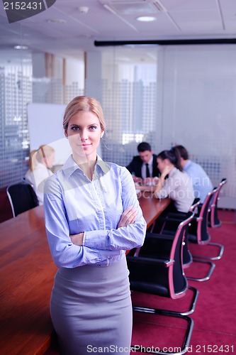 Image of business woman with her staff in background at office