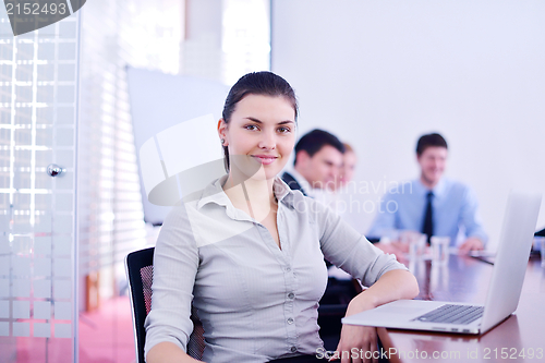 Image of business woman with her staff in background at office