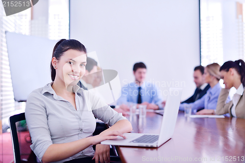 Image of business woman with her staff in background at office