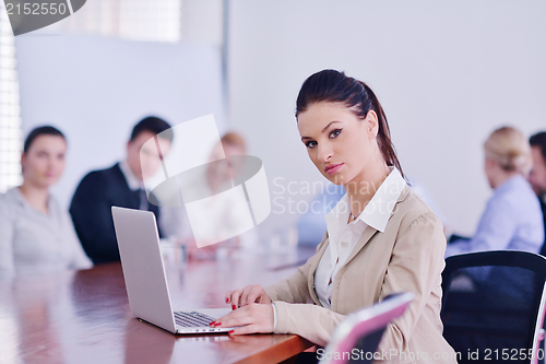 Image of business woman with her staff in background at office