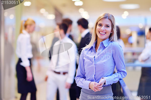 Image of business woman with her staff in background at office