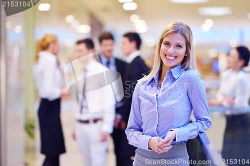 Image of business woman with her staff in background at office