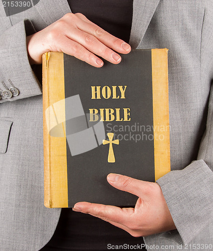 Image of Woman in business suit is holding a holy bible