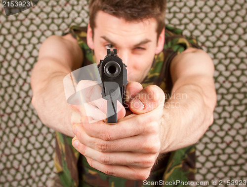 Image of Soldier in camouflage vest is holding a gun