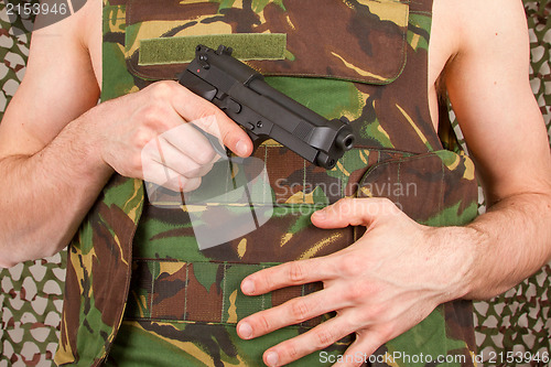 Image of Soldier in camouflage vest is holding a gun