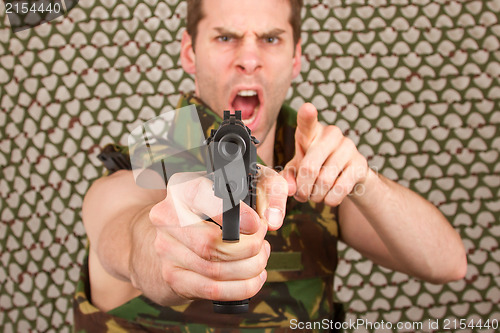 Image of Soldier in camouflage vest is holding a gun