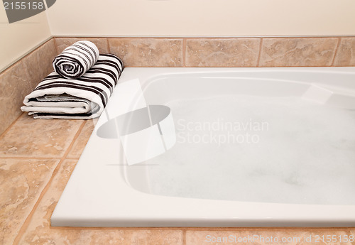 Image of Folded striped towels and bath with foam