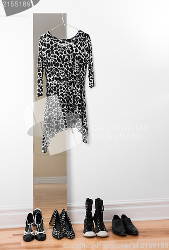 Image of Dress hanging on a mirror, and row of shoes