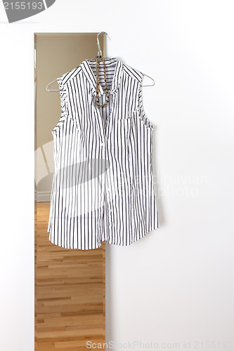 Image of White striped blouse hanging on a mirror