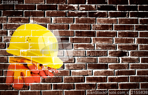 Image of Yellow hard hat and protective gloves with grunge wall backgroun