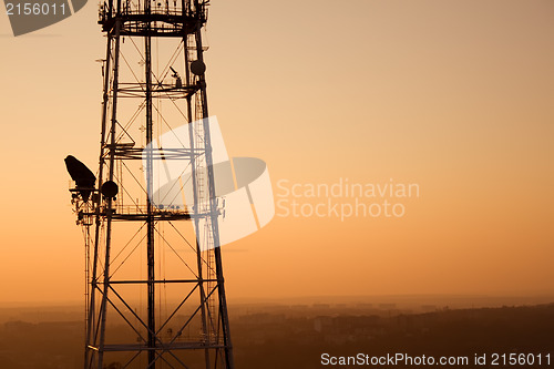 Image of Communication tower at sunset with cityscape